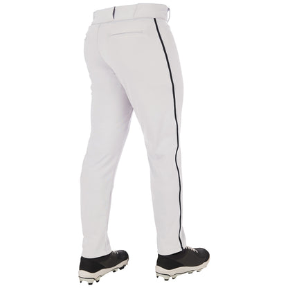 A person stands with their back to a white background, wearing Champro Sports Adult Triple Crown 2.0 Tapered Baseball Pants with black piping (BP66) and black cleats. These pants feature durable pro-weight fabric and a tapered fit.