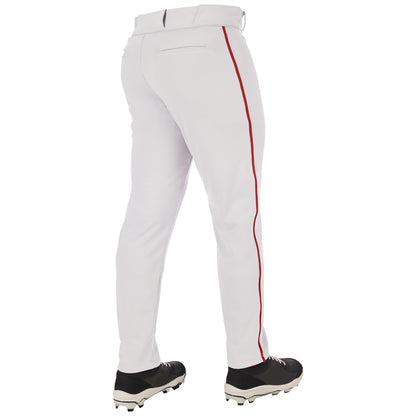 Someone stands with their back to the camera, wearing Champro Sports Adult Triple Crown 2.0 Tapered Baseball Pants with red piping (BP66), made from pro-weight fabric, along with black cleats.
