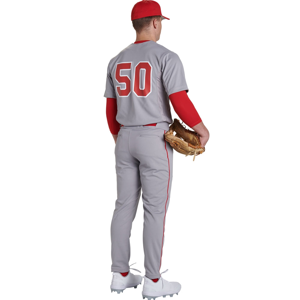 A baseball player in a gray uniform with red trim, a red cap, and number 50 stands holding a glove. He wears Champro Sports Adult Triple Crown 2.0 Tapered Baseball Pants with Piping (BP66), facing away from the camera.