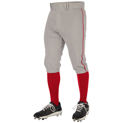 A person wearing Champro Sports Youth Triple Crown 2.0 Knicker Baseball Pants with red piping (BP70Y), paired with red knee-high socks, black and white cleats, and a matching gray belt, shown from the waist down.
