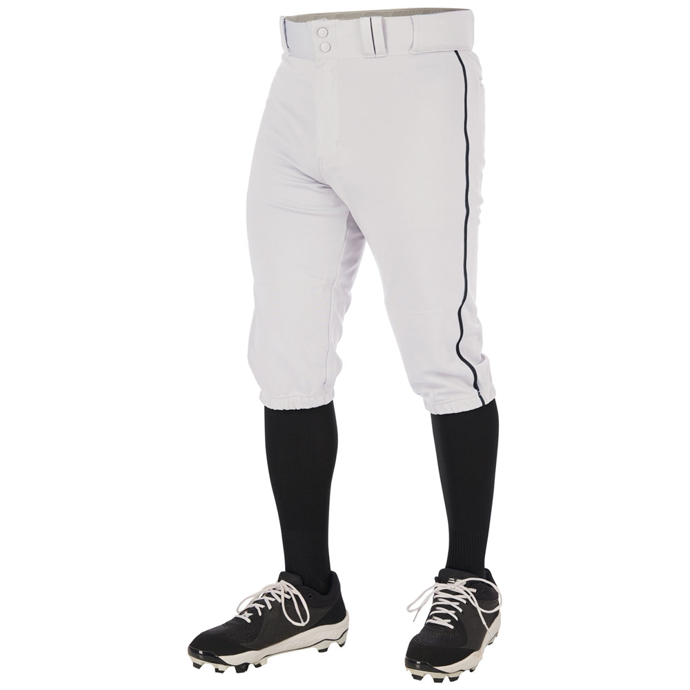 A person wears Champro Sports Youth Triple Crown 2.0 Knicker Baseball Pants with black piping (BP70Y), paired with black knee-high socks and black cleats, shown waist to feet against a white background.