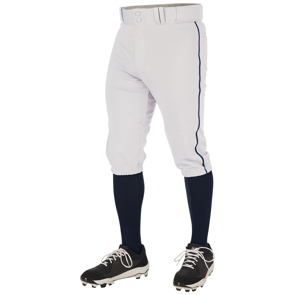 A person, shown from the waist down against a white background, wears Champro Sports Youth Triple Crown 2.0 Knicker Baseball Pants with Piping (BP70Y), black knee-high socks, black cleats, and a white belt.