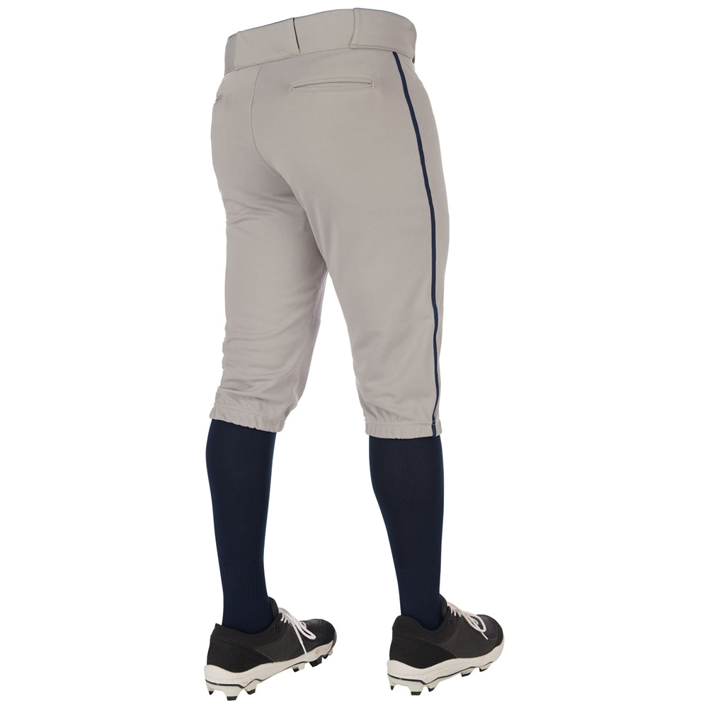 A person is shown from the back, standing on a white background, wearing Champro Sports Youth Triple Crown 2.0 Knicker Baseball Pants with Piping (BP70Y), black cleats, and navy blue knee-high socks.