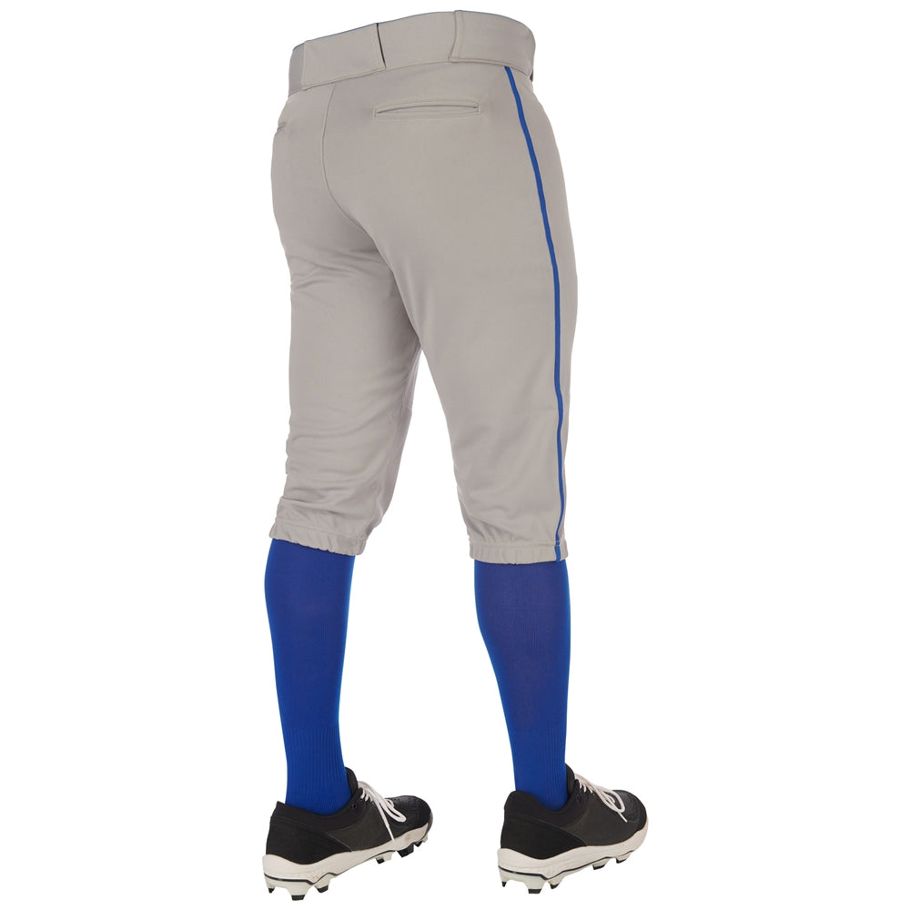 A person wearing Champro Sports Youth Triple Crown 2.0 Knicker Baseball Pants with Piping (BP70Y), blue knee-high socks, and black cleats stands facing away from the camera against a white background.