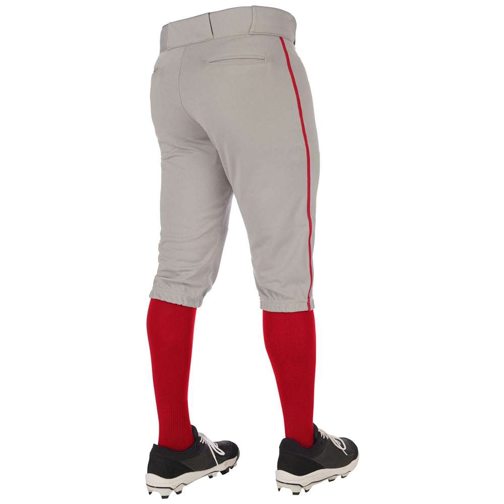 A person is shown from the back wearing Champro Sports Youth Triple Crown 2.0 Knicker Baseball Pants with piping (BP70Y), featuring a gray body, red stripe, red knee-high socks, and black cleats.