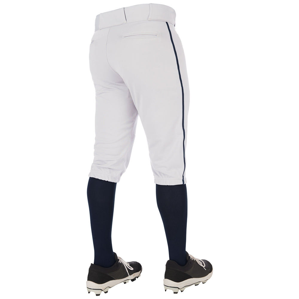 A person wearing Champro Sports Youth Triple Crown 2.0 Knicker Baseball Pants with navy piping, navy knee-high socks, and black cleats stands with their back to the camera against a white background.