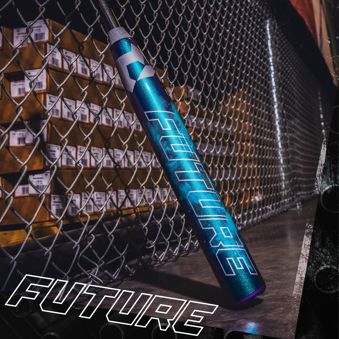 A metallic fastpitch softball bat with "FUTURE" in bold, futuristic lettering rests by stacked boxes near a chain-link fence, evoking the sleek look of the 2026 DeMarini Future (-10) Fastpitch Softball Bat: WBD2674010. "FUTURE" appears bottom left.