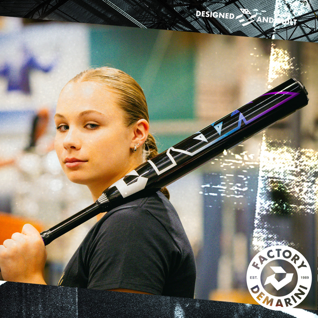 A young woman with blonde hair tied back holds the 2026 DeMarini Prism+ (-11) Fastpitch Softball Bat: WBD2636010 over her shoulder, looking confidently at the camera. The DeMarini logo and Factory badge appear in the corner.