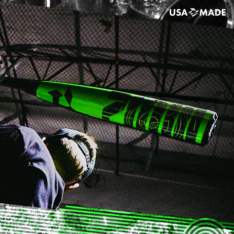 A close-up of a person swinging the 2026 DeMarini ZEN (-8) 2 3/4" USSSA Baseball Bat indoors, with netting and beams behind them. "USA MADE" appears in the top right corner.
