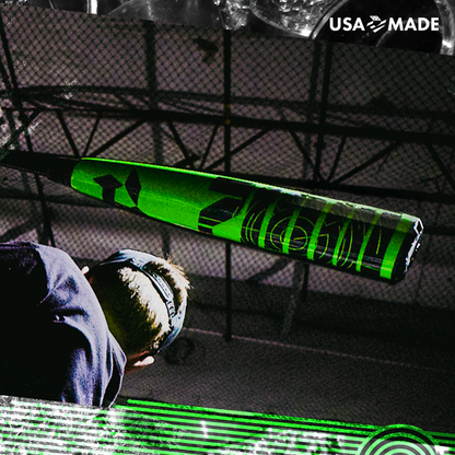 A close-up of a person swinging the 2026 DeMarini ZEN (-8) 2 3/4" USSSA Baseball Bat indoors, with netting and beams behind them. "USA MADE" appears in the top right corner.