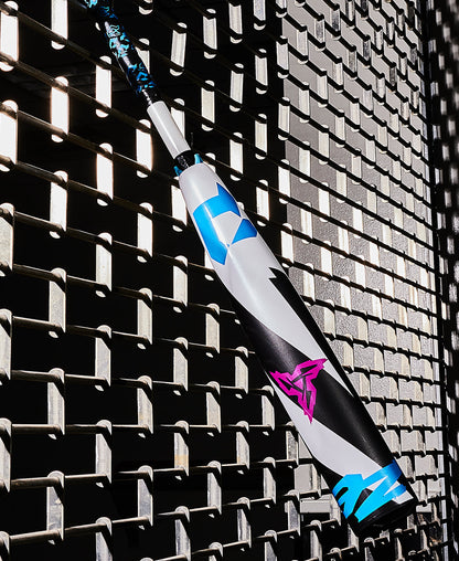 A used 2025 DeMarini ZEN (-10) USSSA Baseball Bat (WBD2532010), featuring blue, white, black, and pink designs, leans against a metal fence casting geometric shadows in the sunlight.