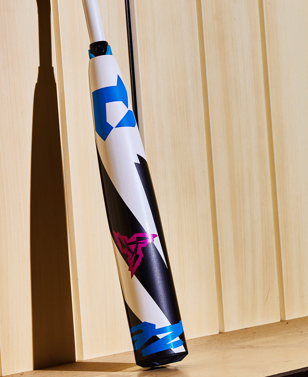 A 2025 DeMarini ZEN (-8) 2 3/4" USSSA Baseball Bat (WBD2533010) with blue, black, and pink geometric designs leans against a light wood-paneled wall, casting a shadow in the background.