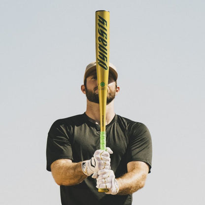 A man in a cap and black shirt, wearing white gloves, holds the 2026 Louisville Slugger Dynasty (-3) BBCOR Baseball Bat (WBL4162010) upright in front of his face against a clear sky.