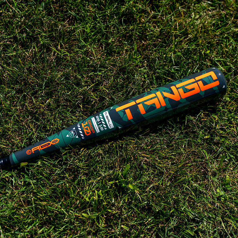 A green and black 2025 Easton Tango (-8) USA Baseball Bat (EUS5TNG8), featuring bold orange "TANGO" lettering, rests on green grass, partially in sunlight.