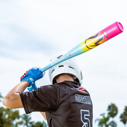 A baseball player in a white helmet and black OHANA #5 jersey gets ready to bat with the 2026 Easton Hype Fire (-5) 2 3/4" USSSA Baseball Bat (EUT6HYP5). Palm trees and sky create a vibrant background.