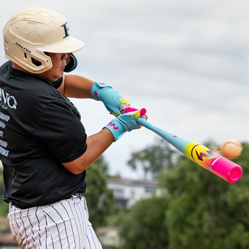 A baseball player in a helmet and gloves swings the 2026 Easton Hype Fire (-8) 2 3/4" USSSA Baseball Bat (EUT6HYP8) outdoors on a cloudy day, with trees and buildings blurred in the background.