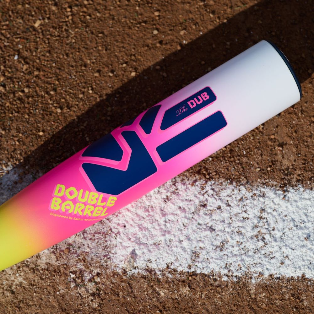 A close-up of the 2026 Easton Dub (-10) 2 3/4" USSSA Baseball Bat by Easton, featuring a pink, yellow, and white gradient design and Double Barrel technology, lies on dirt near a chalk foul line.