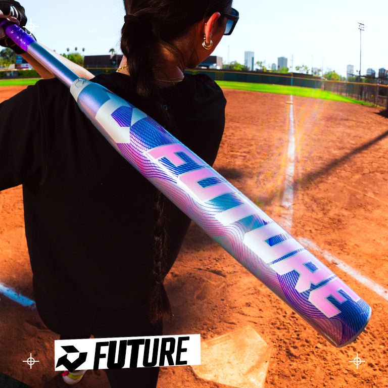 A person stands on a baseball field holding a DeMarini 2027 Future (-10) Fastpitch Softball Bat (WBD2727010) over their shoulder, featuring "FUTURE" in bold and showcasing a Balanced Swing Weight and Dark Matter Composite Gapped Wall Barrel.