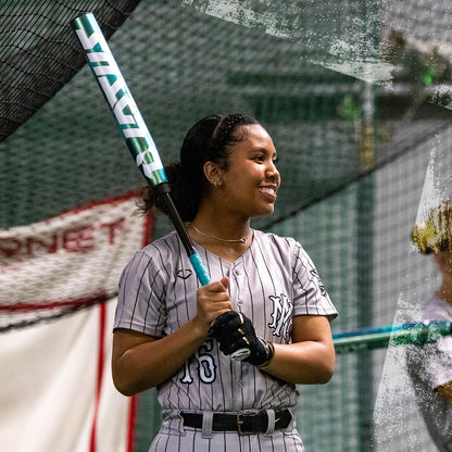 A woman grips the 2026 DeMarini Lotus (-11) Fastpitch Softball Bat (WBD2605010 DEMO), poised to swing with confidence.