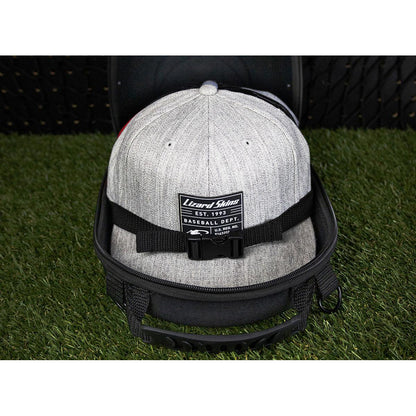 The Lizard Skins Hat Guardian: HATGD100 is a crush-proof case, shown with a gray cap featuring a black strap and Lizard Skins Baseball Dept. EST. 1992 patch, keeping your hat secure and protected on the go.