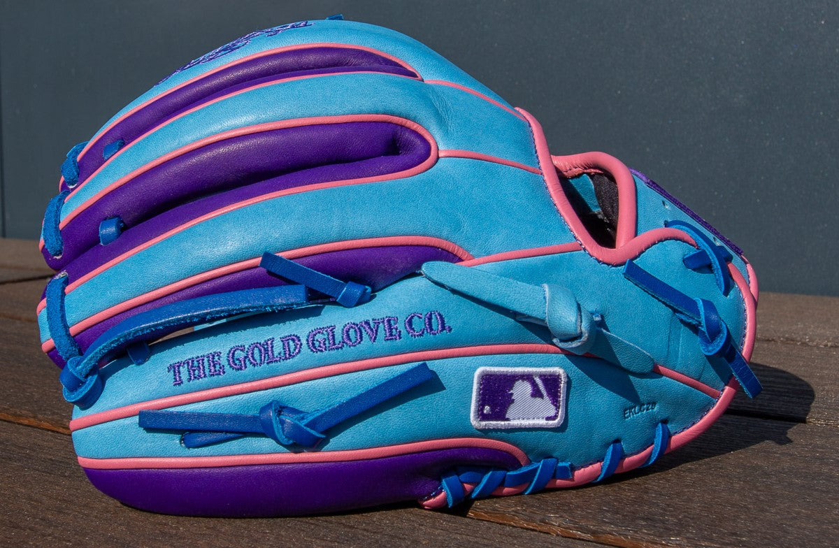 A Rawlings Heart of the Hide 11.5" Color Sync Baseball Glove (PROR314-2CBPU) in light blue with purple and pink accents features THE GOLD GLOVE CO. embroidery and an MLB logo near the wrist, showcasing this stylish Rawlings infield glove.