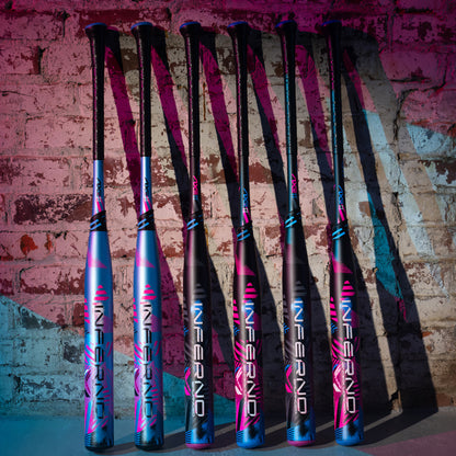 Six 2024 AXE Inferno 12" Maxload NSA USSSA Slowpitch Softball Bats stand upright against a brick wall, blue and pink lights reflecting off their bold design and highlighting AXE’s advanced Hyperflex Barrel Technology.