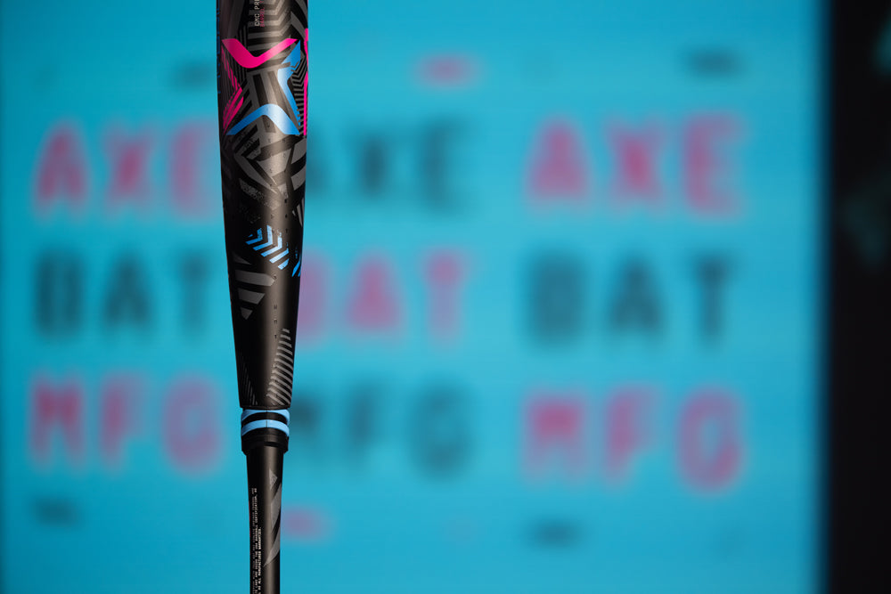 Close-up of the 2024 AXE Avenge Pro 3 Hybrid (-8) USA Baseball Bat (L174M) in black with blue and pink accents, shown against a blurry blue background with "AXE BAT MFG" in pink on the barrel.