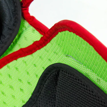 Close-up of a green fabric with black and red stitched trim, possibly part of a sports glove or protective gear, showing textured and breathable material.