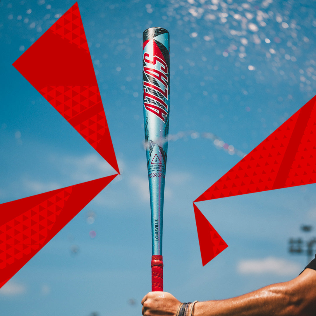 A person holds the 2026 Louisville Slugger Atlas (-3) BBCOR Baseball Bat (WBL4116010) vertically against a vivid blue sky, with bold red geometric shapes in the background adding dynamic energy to the scene.