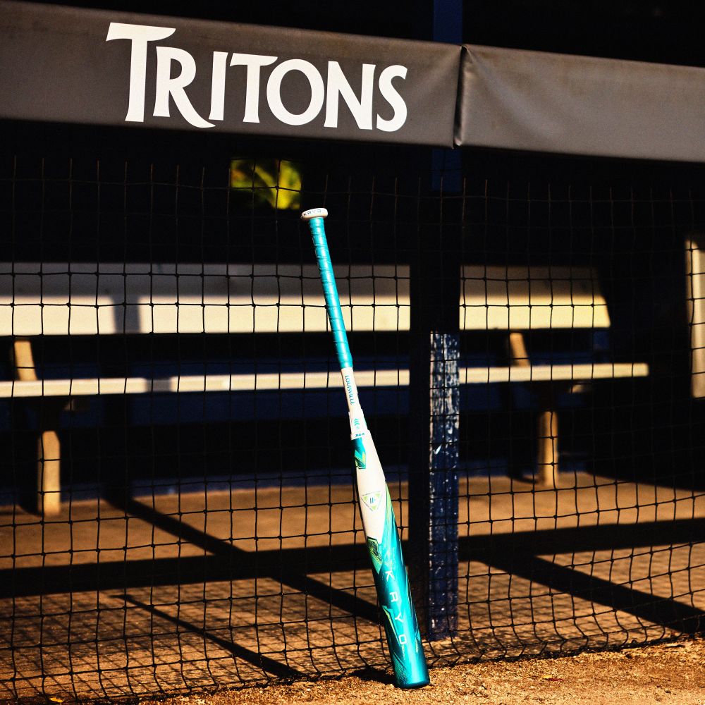 A 2026 Louisville Slugger Kryo (-8) Fastpitch Softball Bat: WBL4137010 (DEMO) leans against a fence.