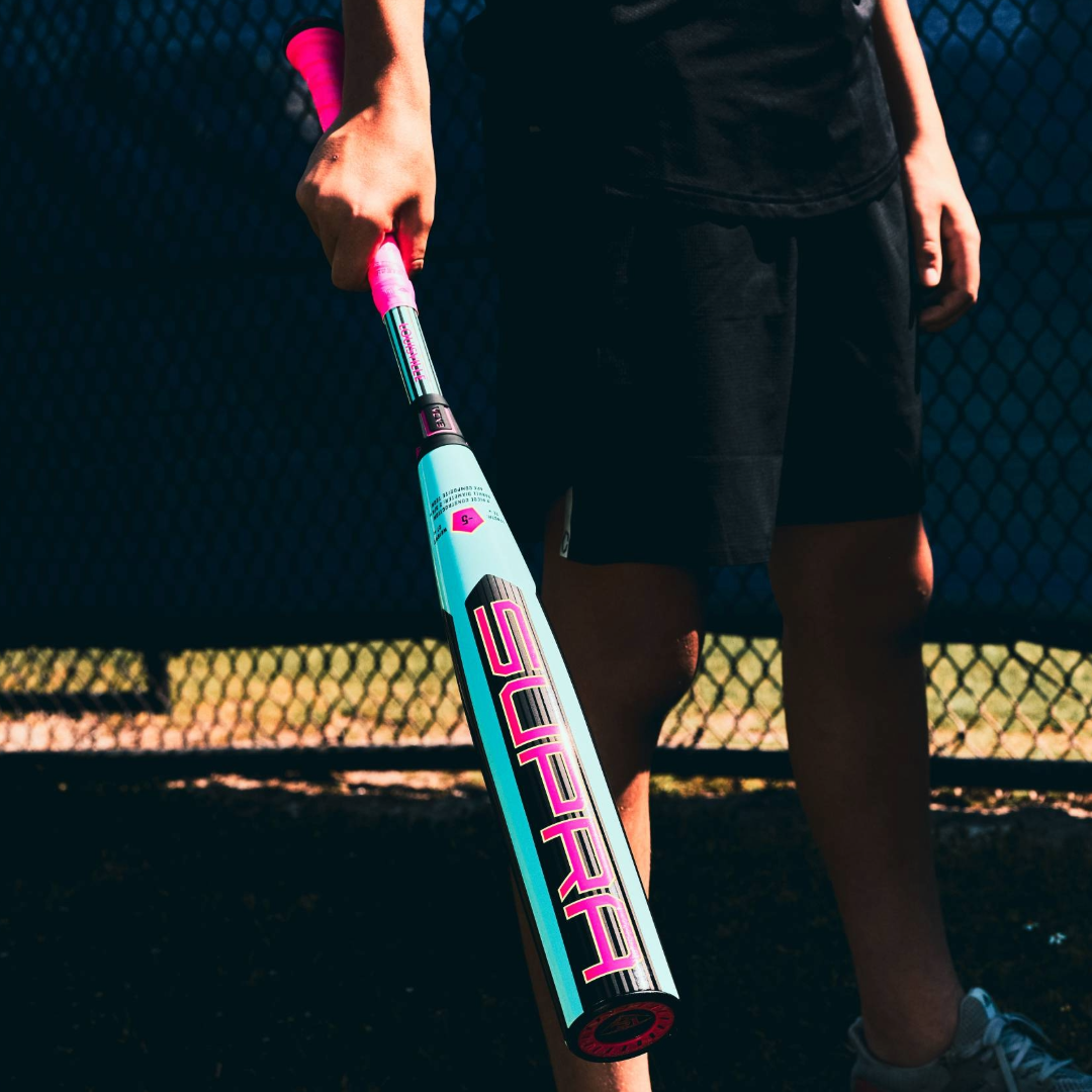 A person in black athletic wear holds the 2026 Louisville Slugger Supra (-5) USSSA Baseball Bat (WBL4120010) near a chain-link fence on a sunny day—the perfect gear for travel ball players.