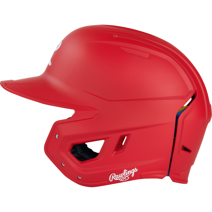 The Rawlings Mach Fit Matte Batting Helmet (MACHFIT) in bright red is shown in profile, featuring ventilation holes, a face guard opening, and a white Rawlings logo near the ear. It includes advanced IMPAX foam technology for enhanced protection.