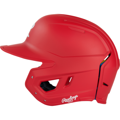 The Rawlings Mach Fit Matte Batting Helmet (MACHFIT) in bright red is shown in profile, featuring ventilation holes, a face guard opening, and a white Rawlings logo near the ear. It includes advanced IMPAX foam technology for enhanced protection.