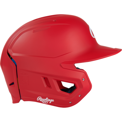 A Rawlings Mach Fit Matte Batting Helmet (MACHFIT) in bright red, featuring a face guard, ventilation holes, and IMPAX foam technology for protection, is shown from the side on a plain white background.