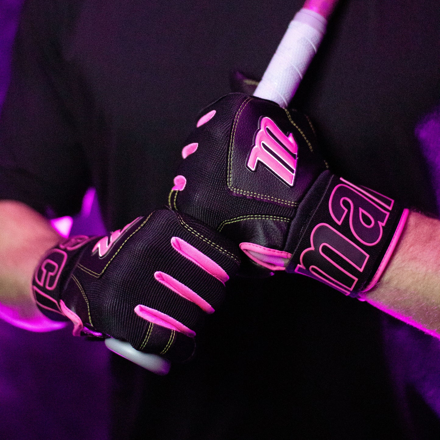 A person wearing Marucci Blacksmith V2 Full Wrap Adult Batting Gloves (MBG2BKSM) grips a baseball or softball bat with both hands, standing against a purple-lit background.