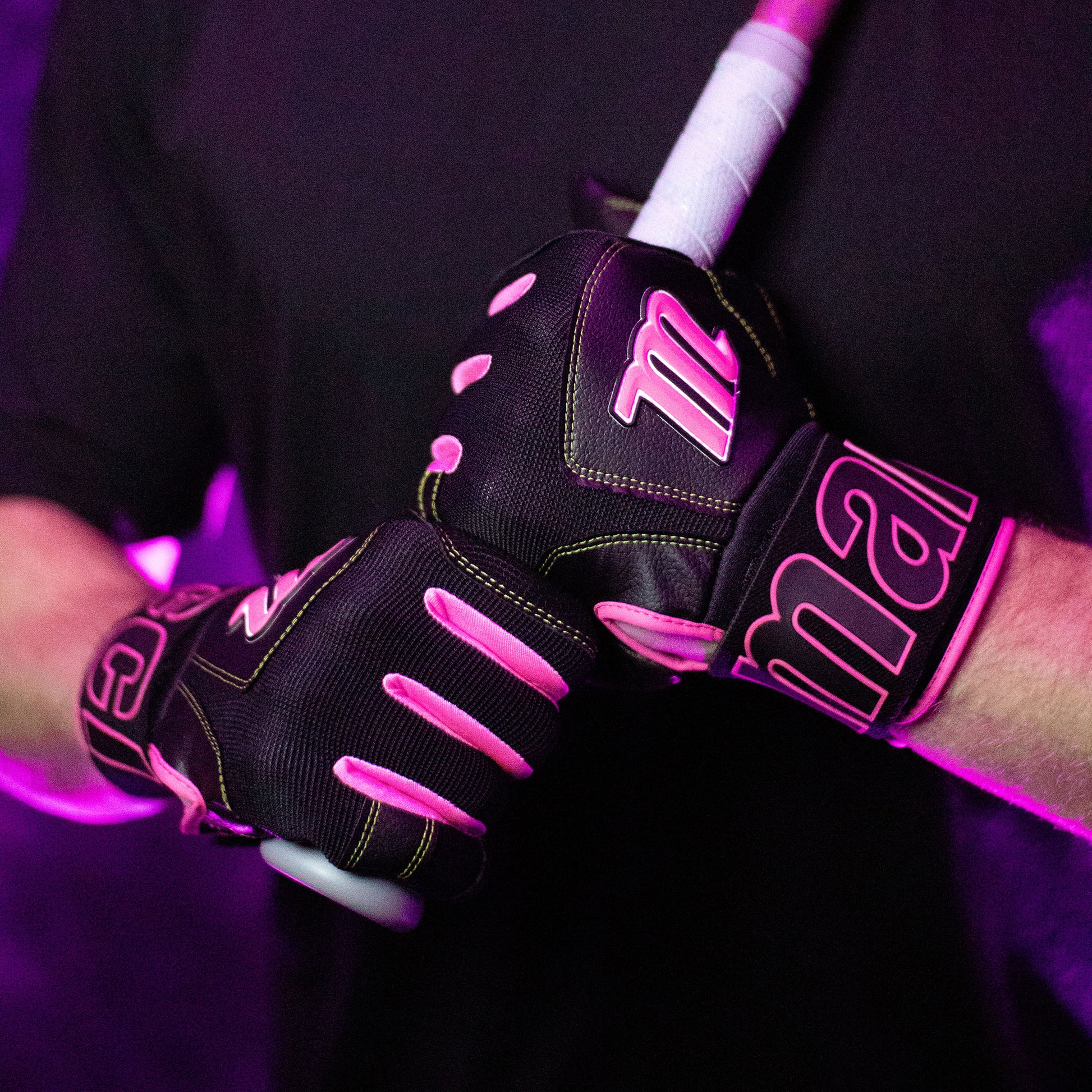 A person wearing Marucci Blacksmith V2 Full Wrap Adult Batting Gloves (MBG2BKSM) grips a baseball or softball bat with both hands, standing against a purple-lit background.