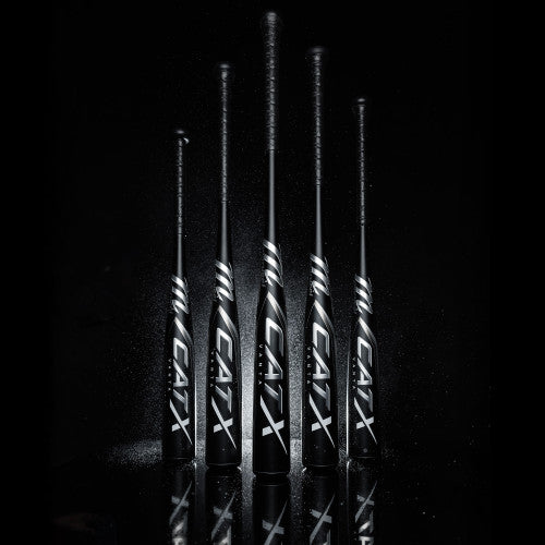 Five black CATX baseball bats, standing vertically on a dark surface with a black background, are arranged in a row with light highlighting their white logos and details.