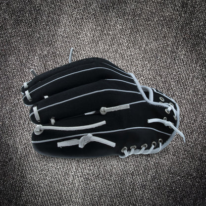 A Marucci NightShift CHUCK T 11.5" Baseball Glove (MFGNTSHFT-0103) from Marucci with white laces is shown closed on a textured gray surface.