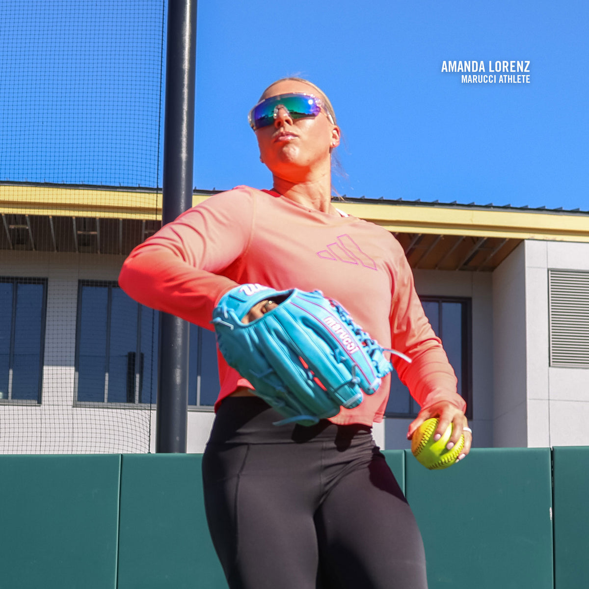 A softball player in sunglasses holds a Marucci NightShift Lorenz 12.5″ Fastpitch Glove: MFGNTSHFT-0305 and ball on a sunny field, with Amanda Lorenz Marucci Athlete text near her shoulder.