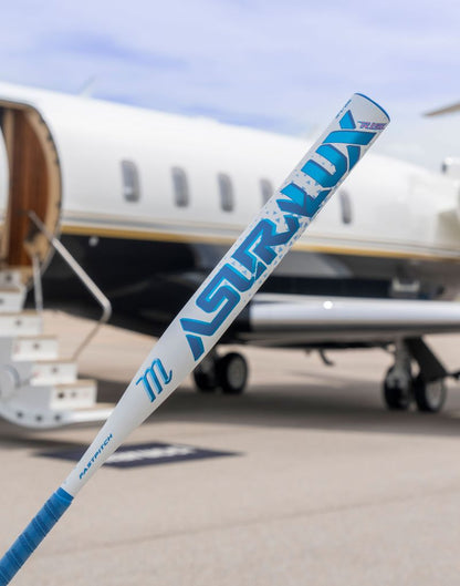 A Marucci 2027 ASURA Lux Rise (-11) Fastpitch Softball Bat (MFPASLR11), featuring Rise Sync Barrel Technology, is held upright in front of a private jet with stairs leading to its open door on an airport tarmac.