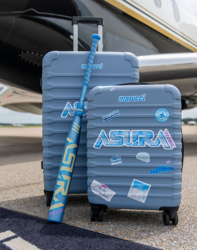 Two blue suitcases adorned with travel stickers stand beside the steps of a private jet on an airport tarmac, with the Marucci 2027 ASURA Rise (-10) Fastpitch Softball Bat (MFPASR10), featuring an anti-vibration knob and signature Marucci styling, leaning against them—perfectly capturing that sweet spot where style meets adventure.