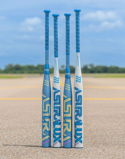 Four blue and white Marucci 2027 ASURA Rise (-10) Fastpitch Softball Bats (MFPASR10) stand upright on pavement, each featuring an anti-vibration knob for added comfort and engineered for fastpitch performance. In the background, a grassy field and blue sky frame the scene, highlighting these bats’ impressive sweet spot for top-level play.