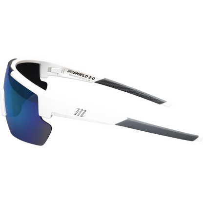 The Marucci Shield 2.0 Performance Sunglasses (MSNVSHIELD2) are sporty white shades with blue mirrored lenses, gray rubberized temple tips, and an M logo on the arm, shown against a plain light background.