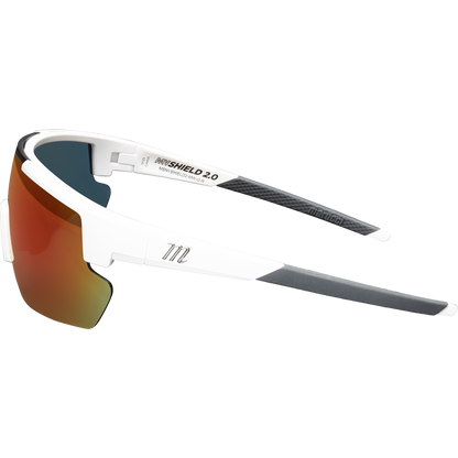 The Marucci Shield 2.0 Performance Sunglasses (MSNVSHIELD2) feature a white and black semi-frameless design, orange-tinted wraparound lenses, and visible Marucci branding on the arms, shown in side profile on a plain background.