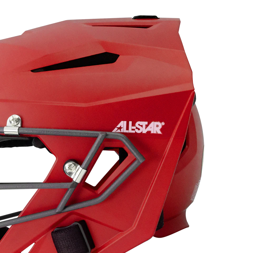 Close-up of a red All-Star branded sports helmet with a black metal faceguard and visible ventilation slits, showing part of the side and front sections.