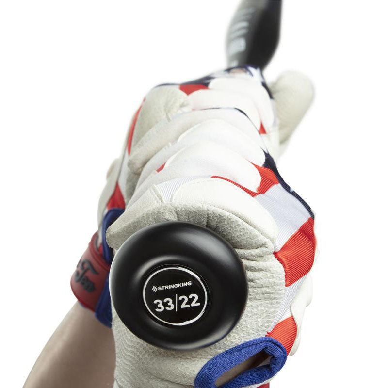 A person wearing white, red, and blue batting gloves grips the handle of a black baseball bat. The bat’s knob shows the brand StringKing and the size 33/22.
