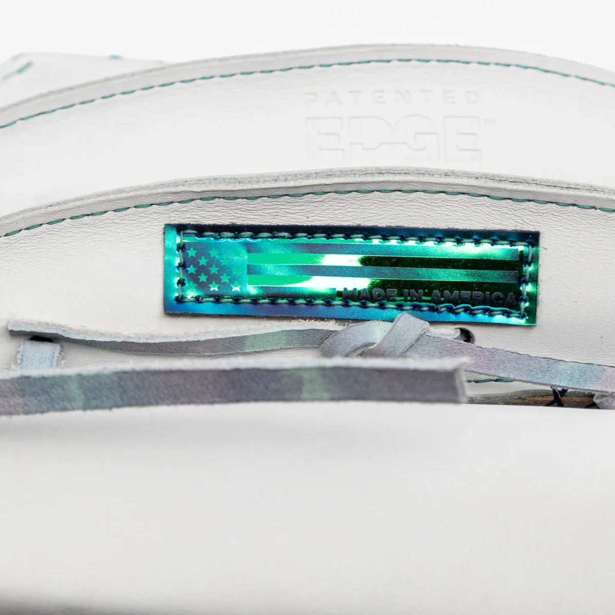 Close-up of a white AmericanKIP leather Nokona Halo 12.5″ Fastpitch Glove: WHT-EP1250H featuring a metallic green American flag label and the word EDGE embossed above it.
