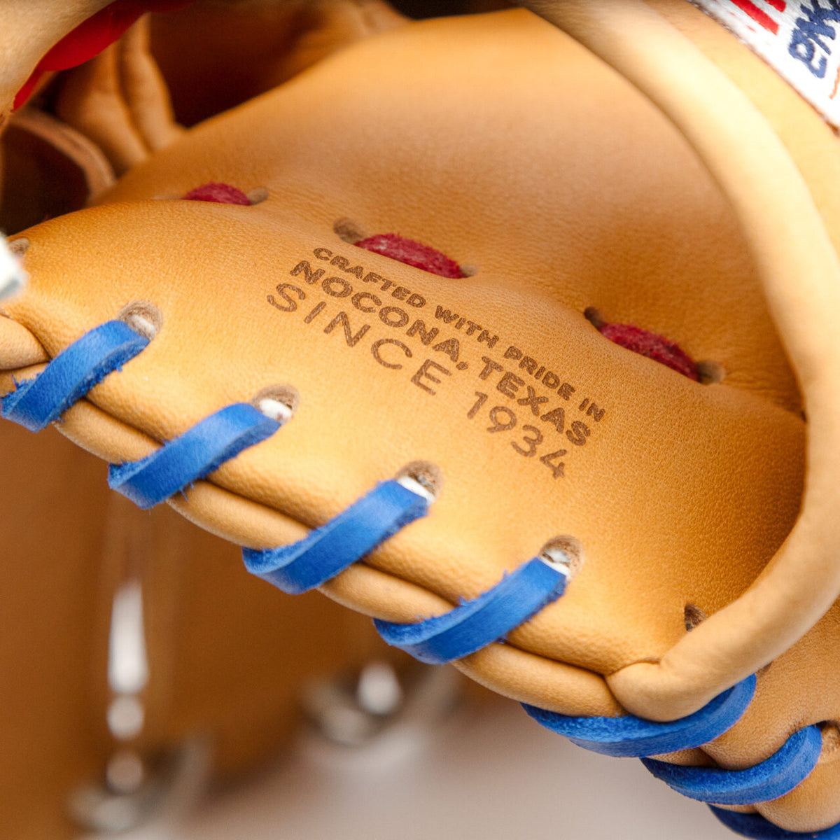 Close-up of a tan Supersoft Steerhide Nokona S1 All-American 12.5″ Baseball Glove: S1-EP800POP with blue lacing, featuring a stamp that reads Crafted with pride in Nocona, Texas since 1934.
