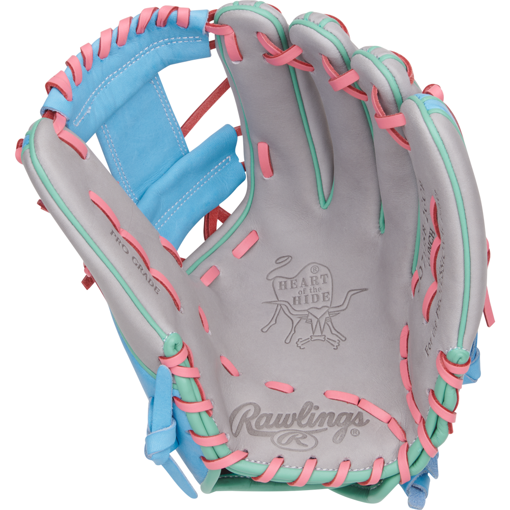The Rawlings Heart of the Hide 12" Fastpitch Glove (PRO716SB-2GCB) features gray leather, pink and teal laces, blue accents, and displays the iconic Rawlings logo and Heart of the Hide branding inside the open palm.