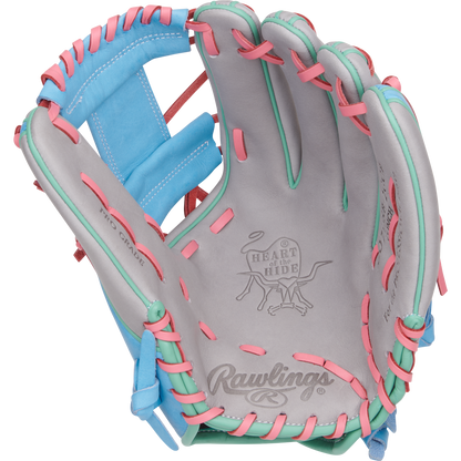 The Rawlings Heart of the Hide 12" Fastpitch Glove (PRO716SB-2GCB) features gray leather, pink and teal laces, blue accents, and displays the iconic Rawlings logo and Heart of the Hide branding inside the open palm.